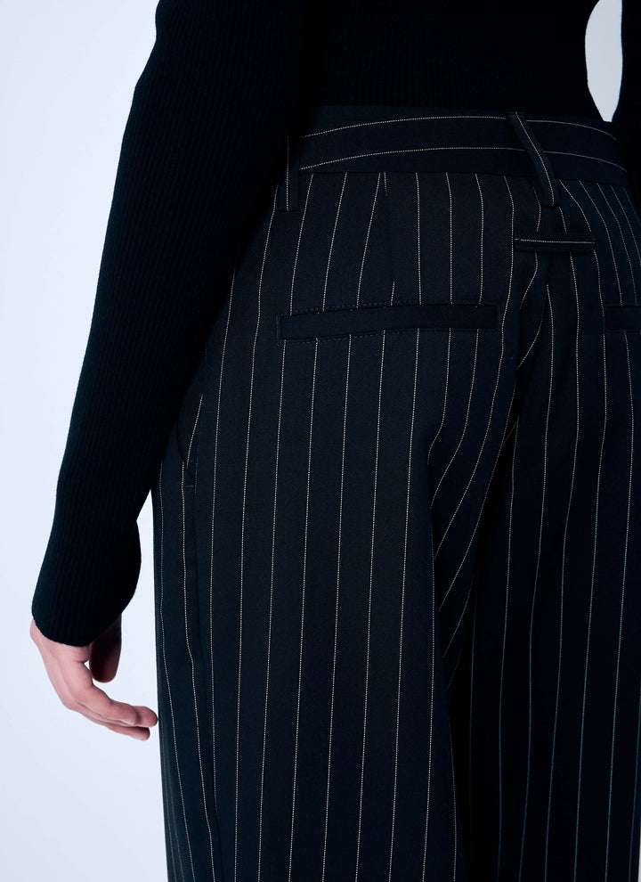 Black pinstripe pants worn by a person on a light gray background