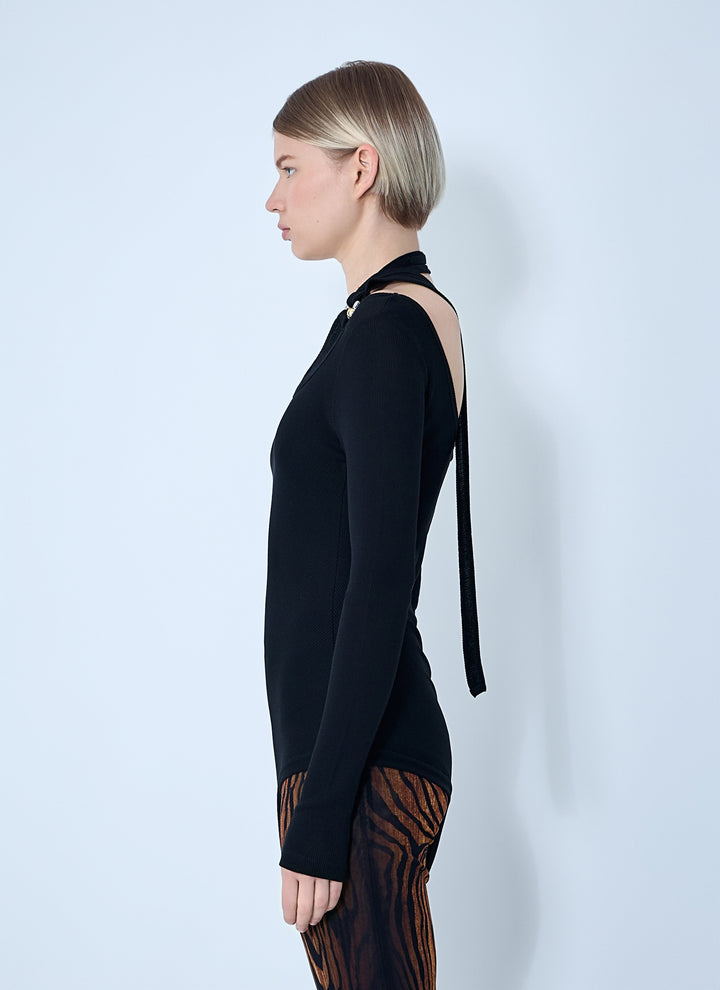 Woman wearing a black dress with cut-out shoulders against a white background