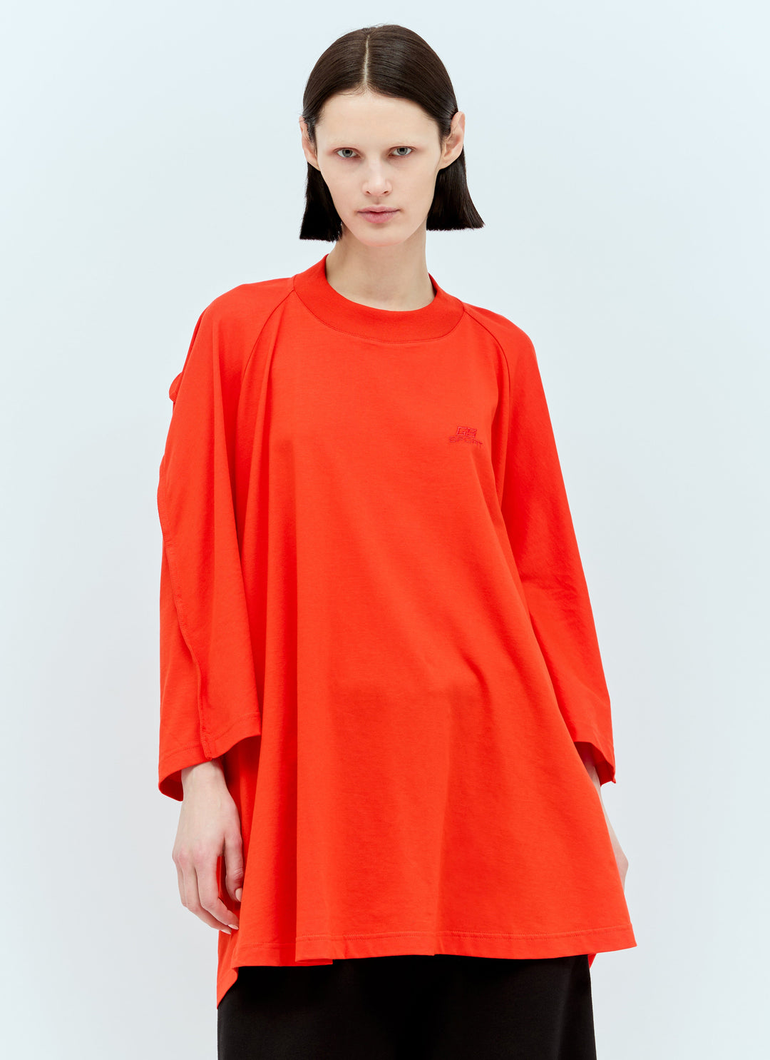 Person wearing a bright orange long-sleeve top on a light gray background