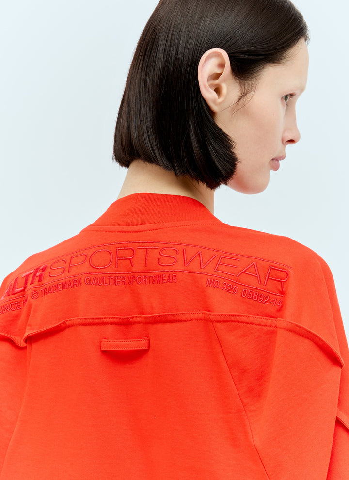 Person wearing a bright orange sports jacket with branding on a light gray background