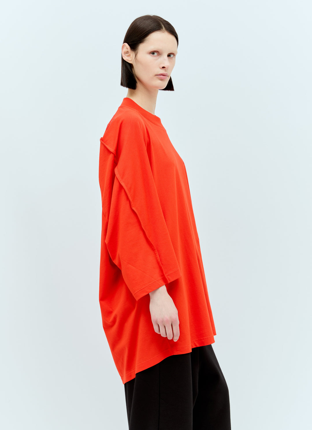 Person wearing a bright orange top on a light gray background
