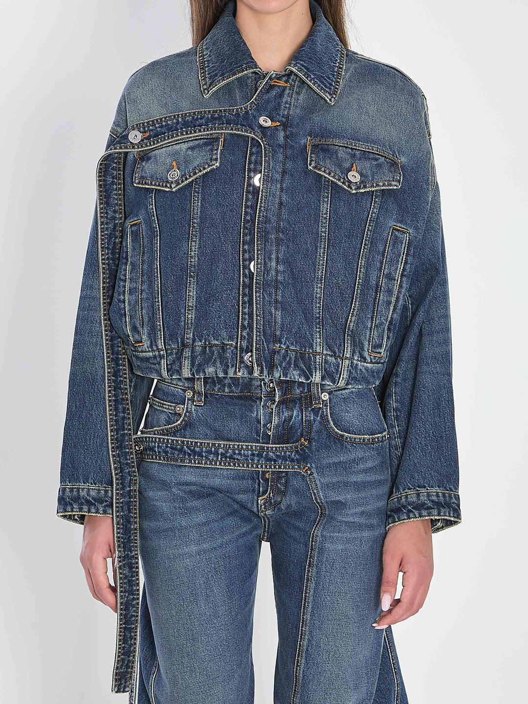 Person wearing a blue denim jacket and jeans on a white background
