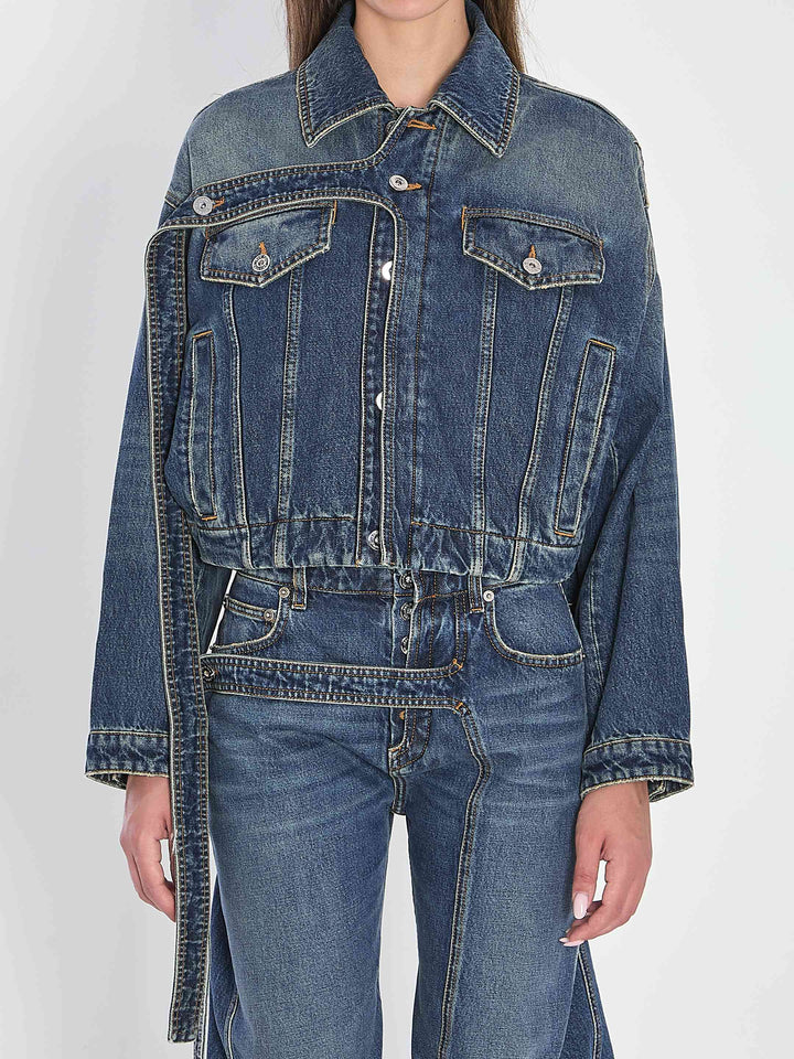 Person wearing a blue denim jacket and jeans on a white background