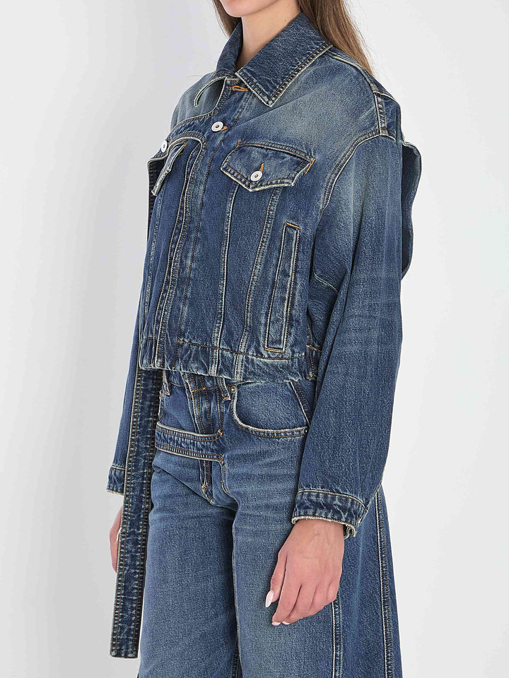 Person wearing a blue denim jacket and jeans on a white background