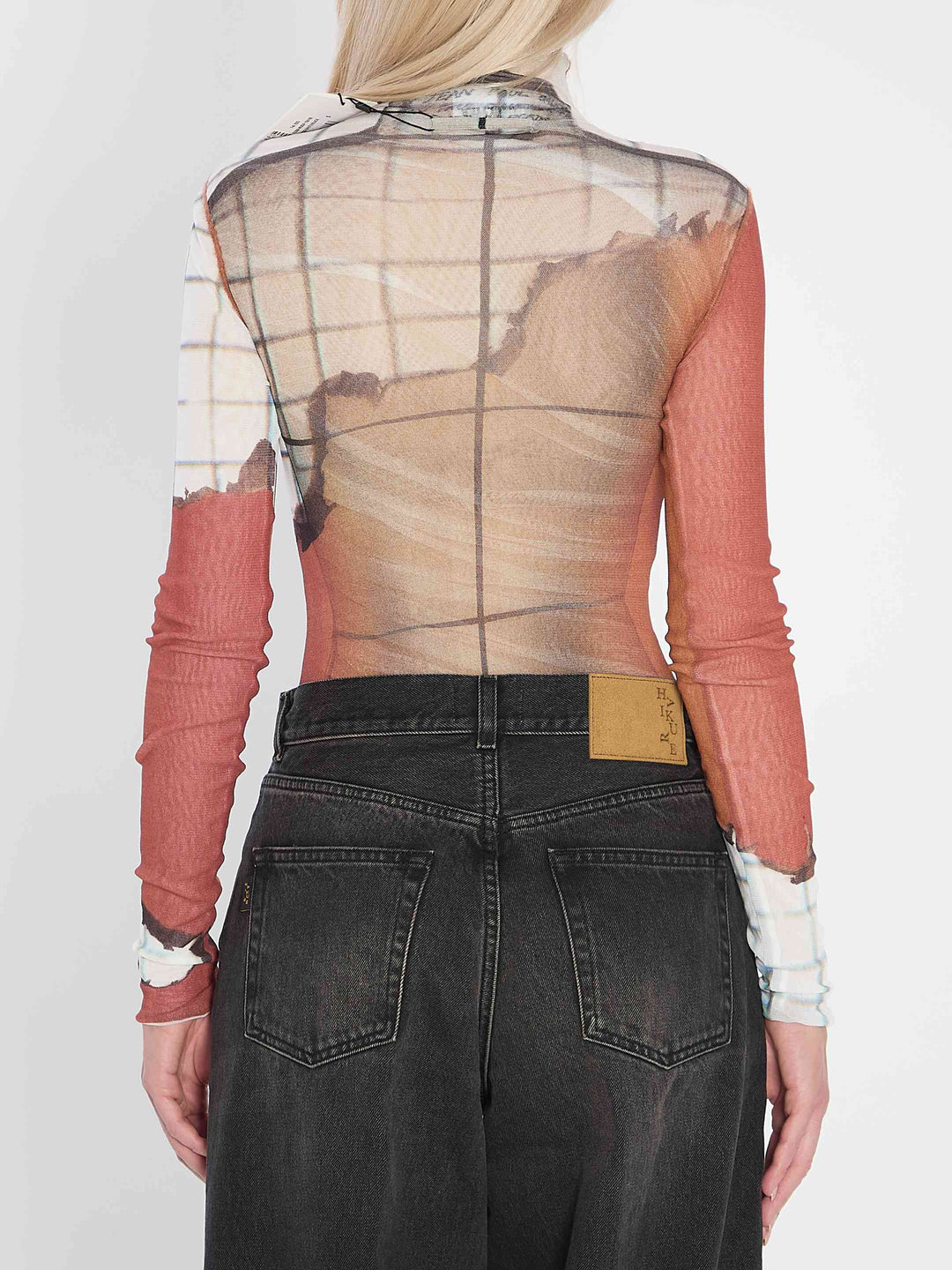 Person wearing a sheer top with red sleeves and black pants on a white background