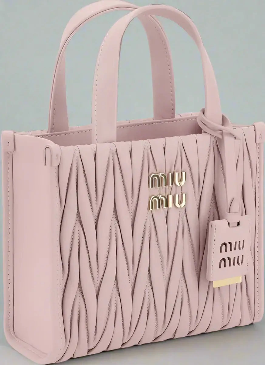 Pink textured handbag with 'Miu Miu' logo on a white background
