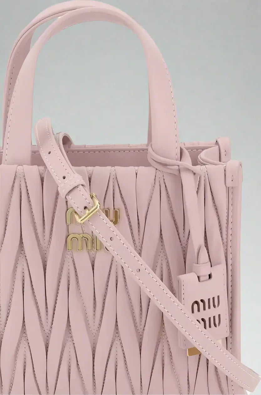 Pink textured handbag with a strap featuring the Miu Miu logo on a white background