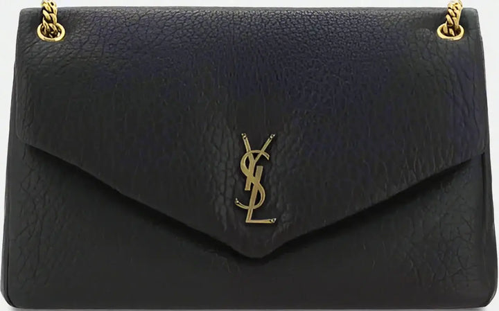 Black leather handbag with gold chain and logo on a black background