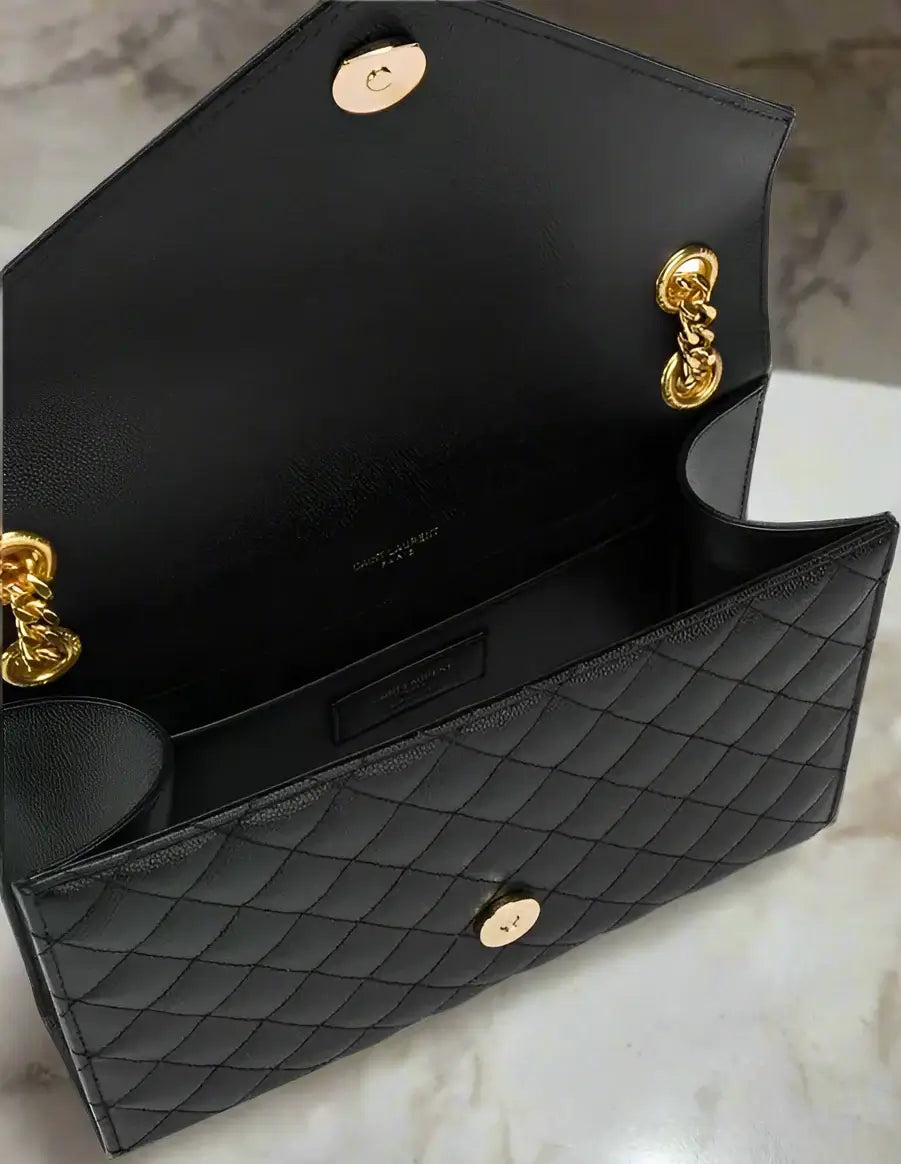 Black quilted handbag with gold hardware on a white background