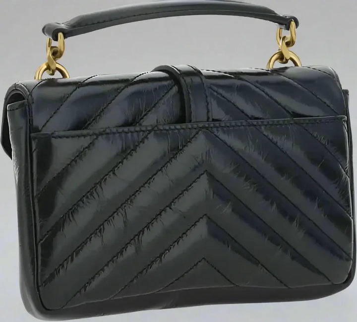 Black quilted handbag with gold handles on a white background