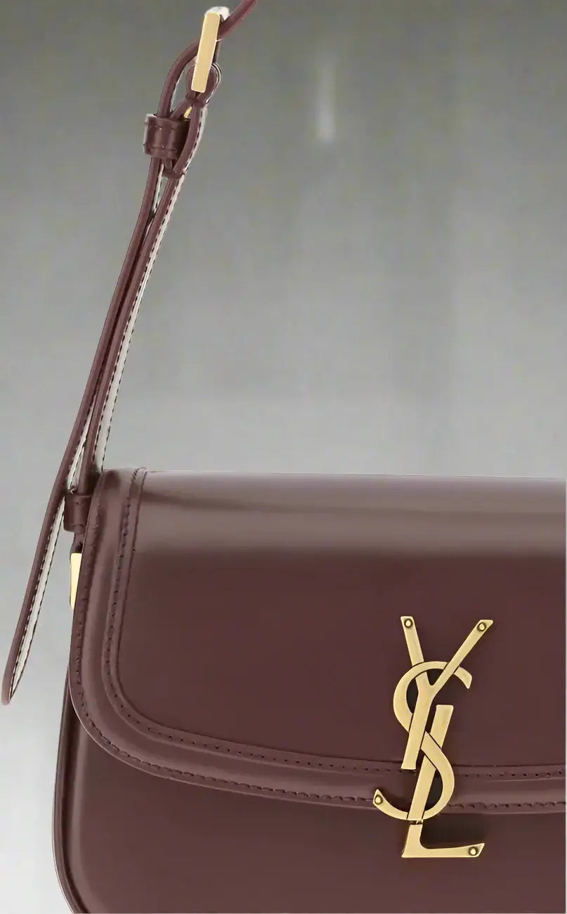 Brown leather handbag with gold logo on a white background