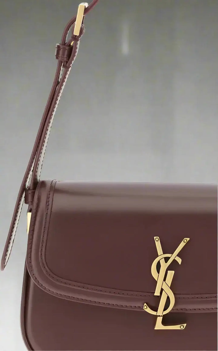 Brown leather handbag with gold logo on a white background