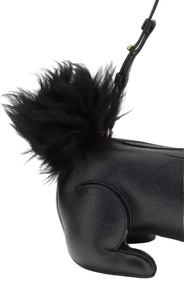 Black leather dog-shaped bag with a fluffy black pom-pom on a white background