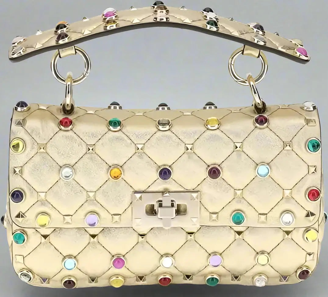 Gold quilted handbag with colorful gemstones on a white background