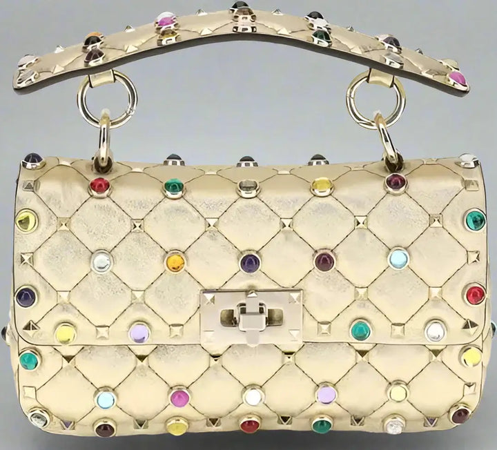 Gold quilted handbag with colorful gemstones on a white background