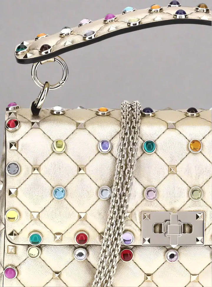 Luxury handbag with colorful gemstones and a chain detail on a white background