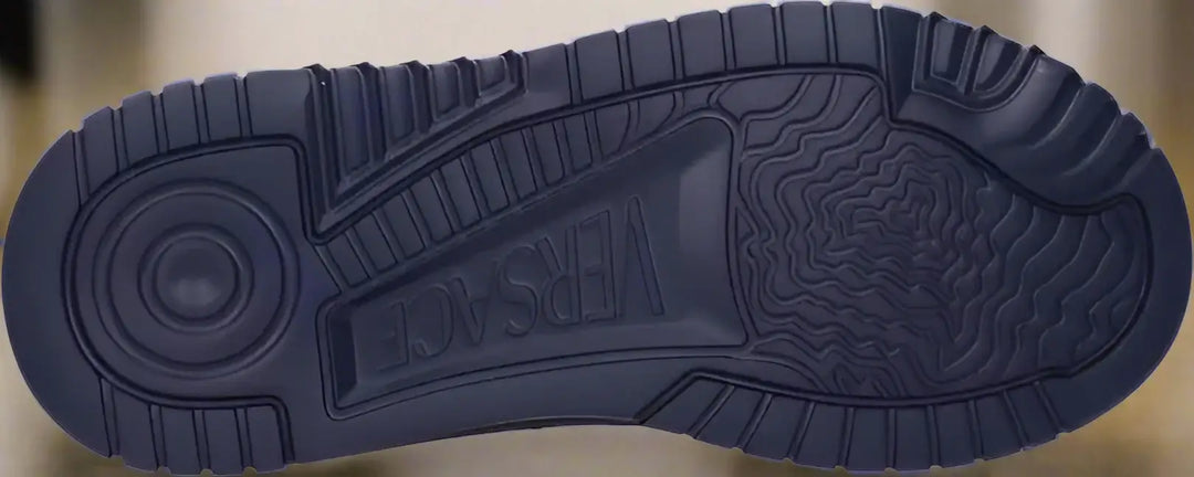 Navy blue sneaker sole with 'Versace' branding on a white background