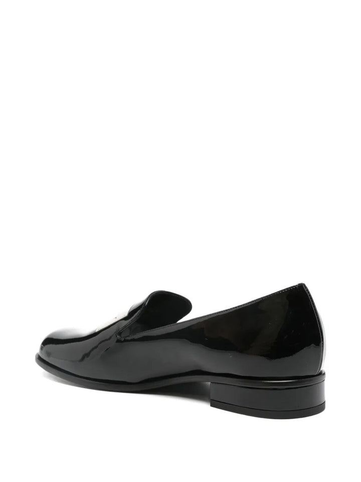 Black patent leather loafer on a white background