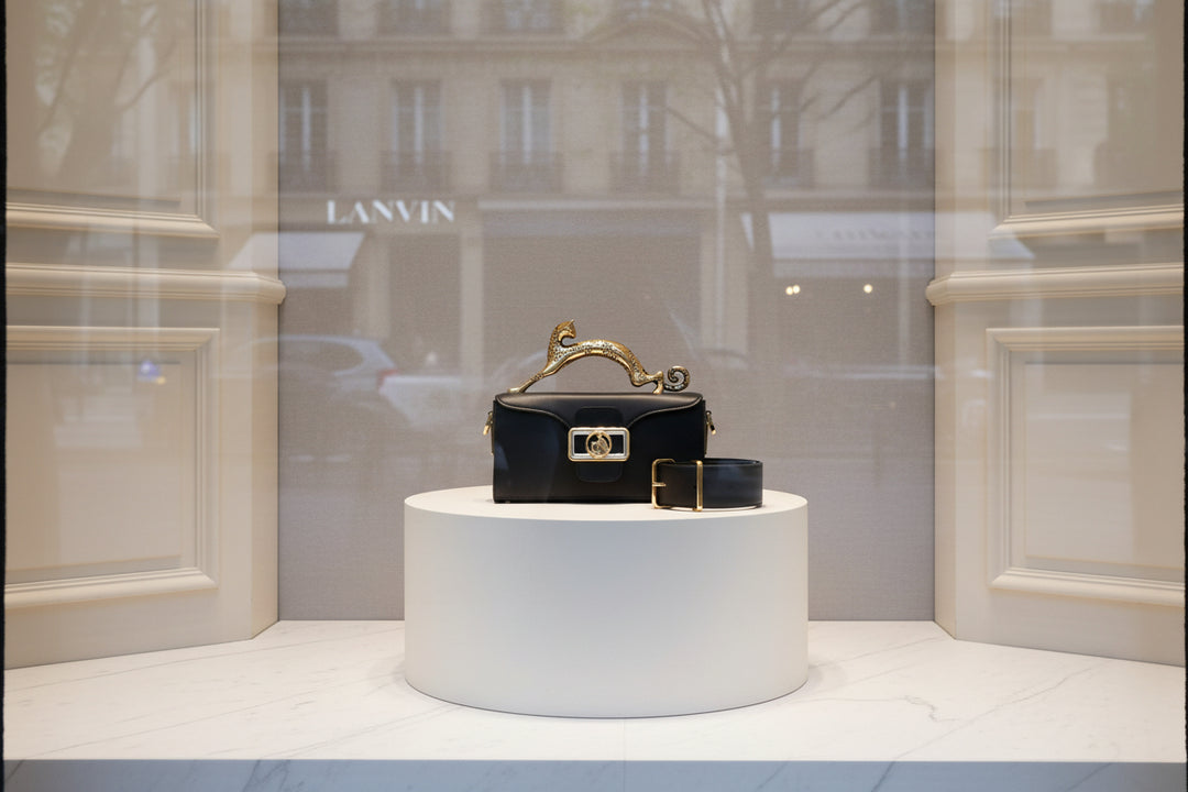 Black handbag with gold panther handle and clasp on a white background