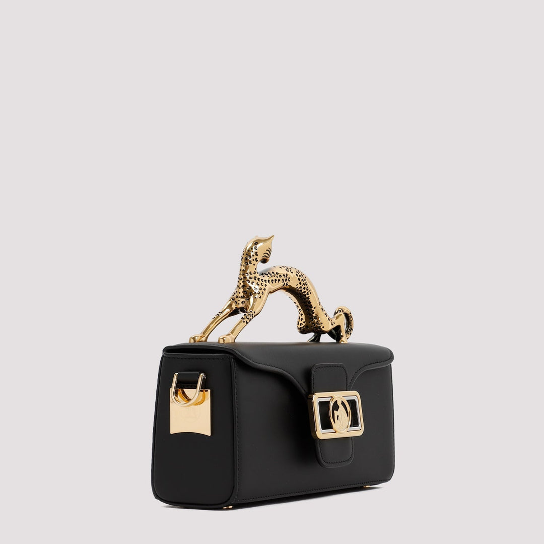 Black handbag with gold accents and a decorative figure on a light gray background