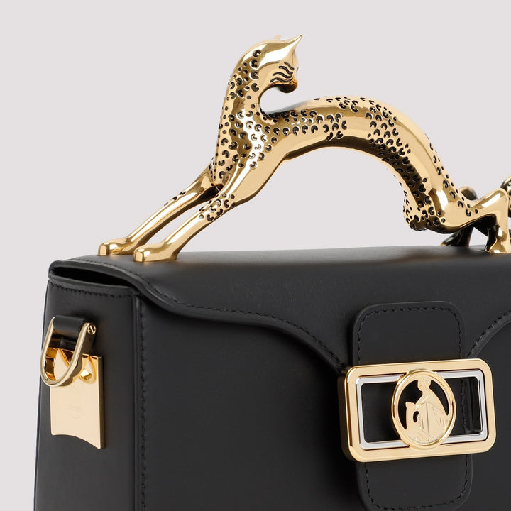 Black handbag with gold handle and decorative clasp on a light gray background