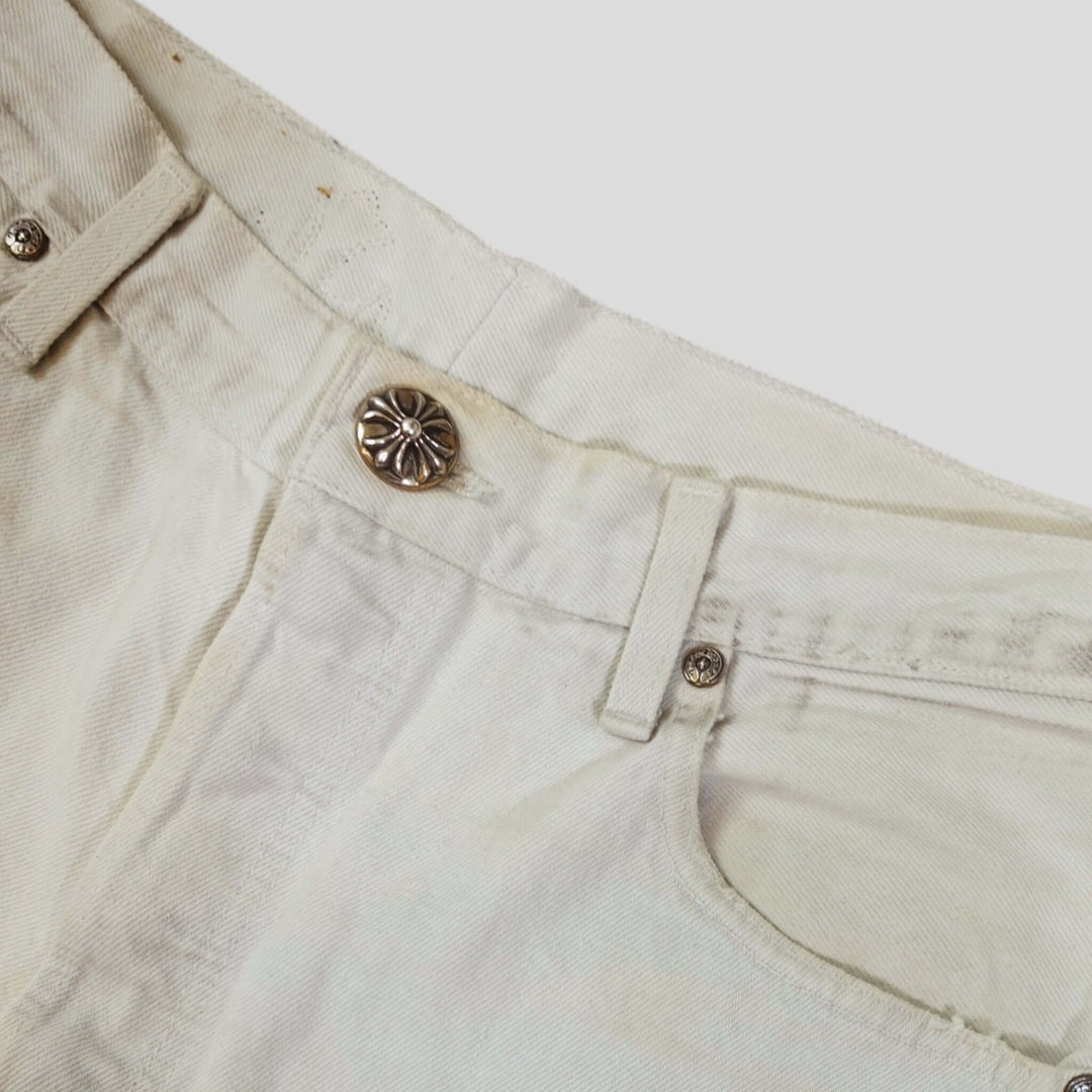 Close-up of Chrome Hearts Leopard Cross Patch Jeans in White featuring signature button detail.