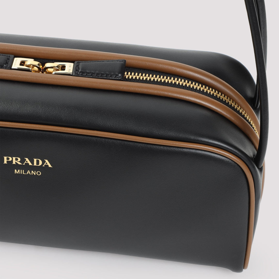 Black Prada bag with gold zipper on a light gray background