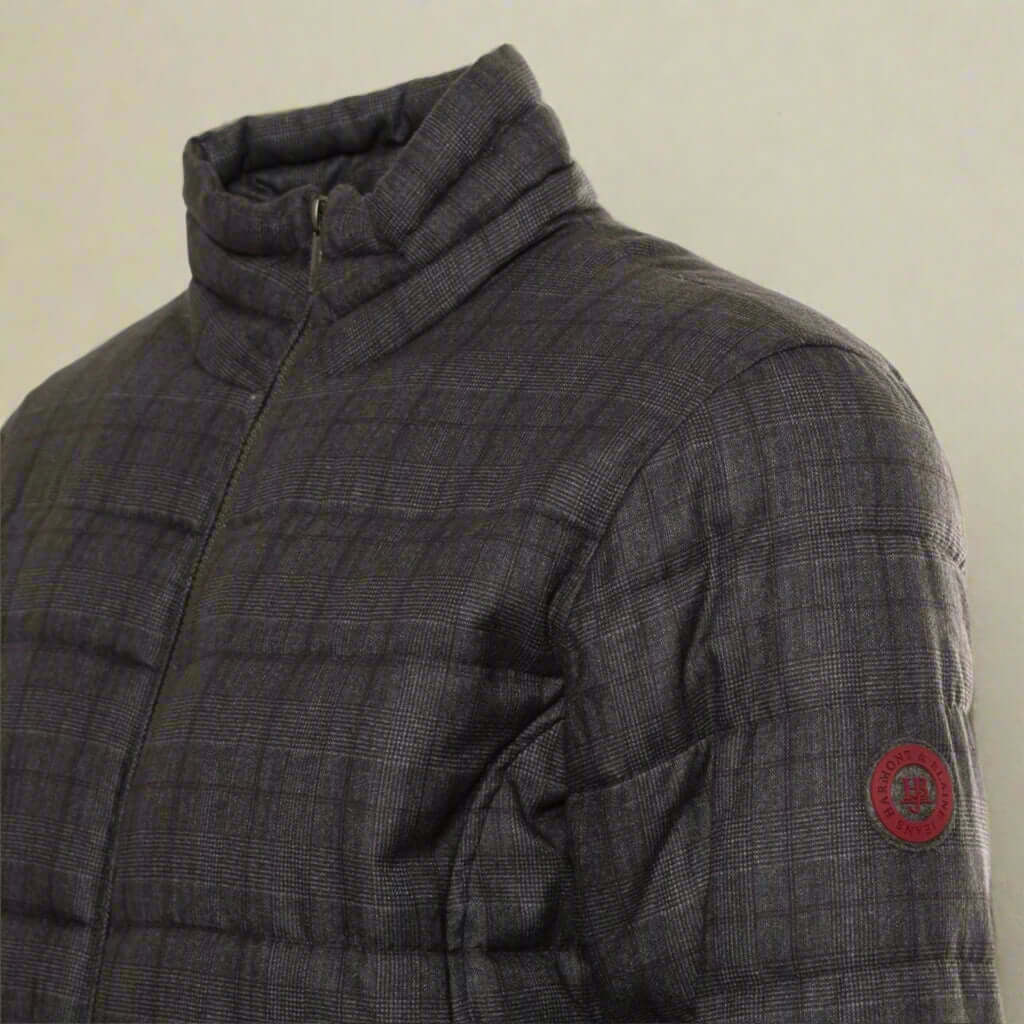 Gray quilted jacket with a red logo patch on a white background