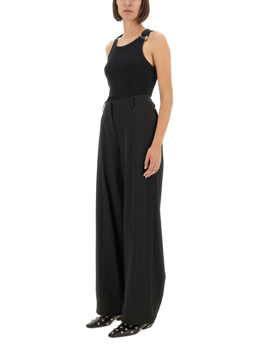 Person wearing a black sleeveless top and wide-leg pants on a white background