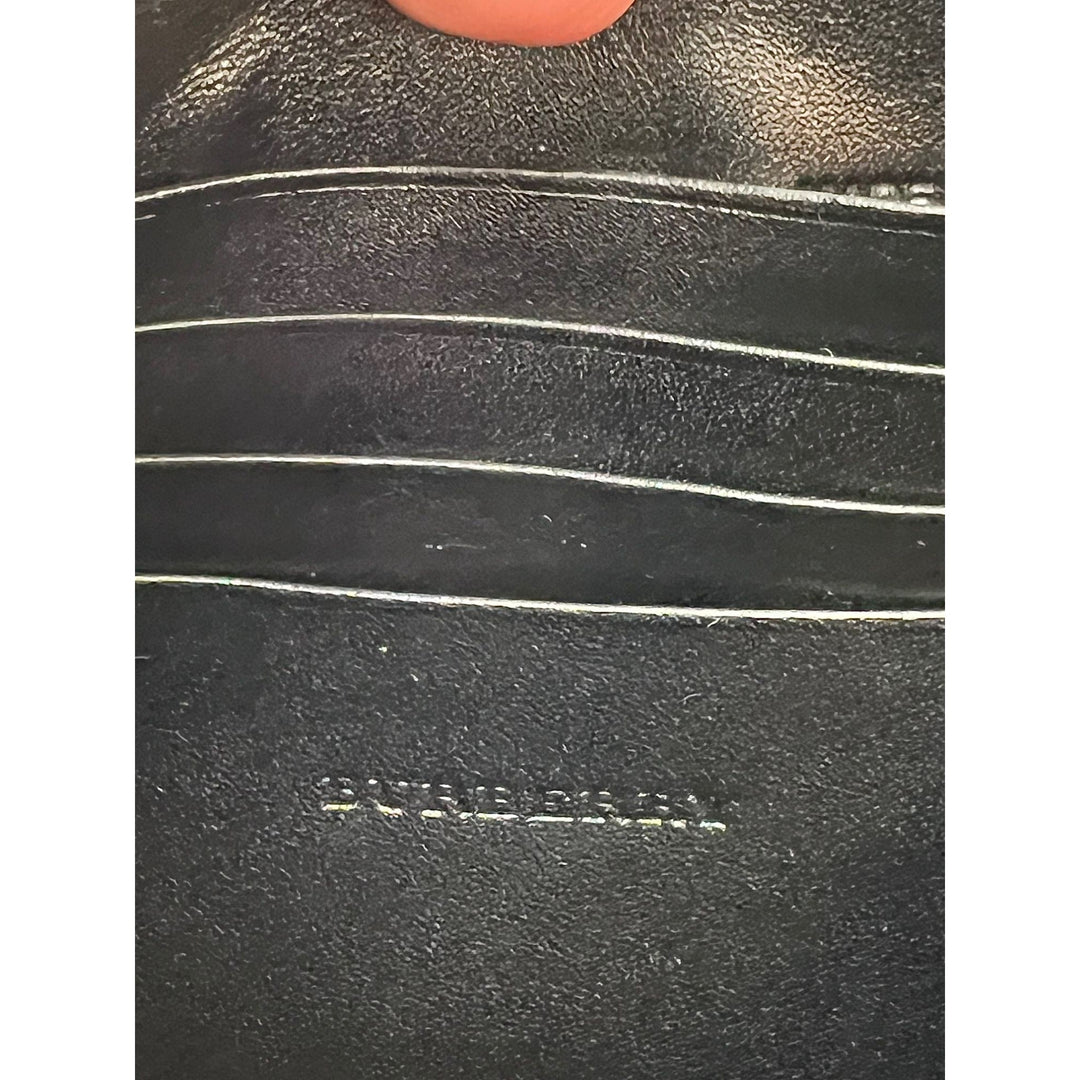 Close-up of a black leather product with 'Burberry' branding.