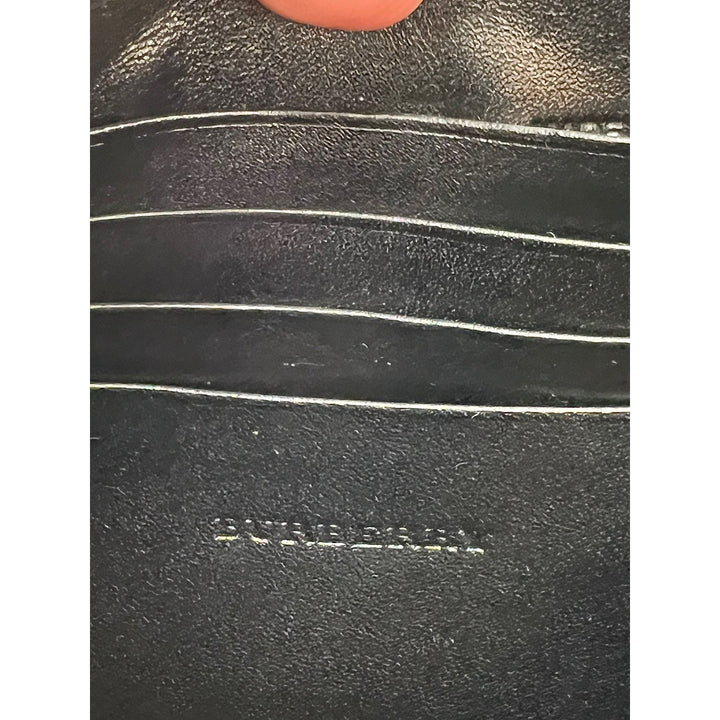 Close-up of a black leather product with 'Burberry' branding.