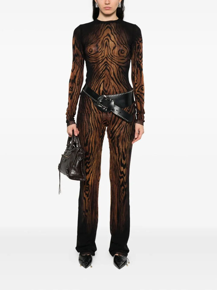 Person wearing a black and brown patterned outfit with a belt and handbag on a white background