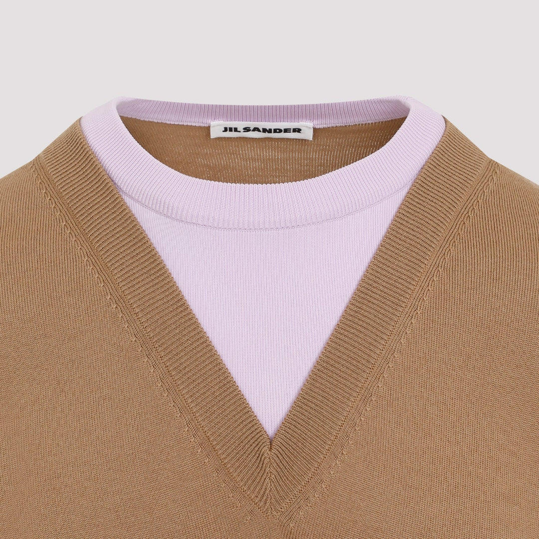Close-up of a beige sweater with a pink collar and 'Jil Sander' label.