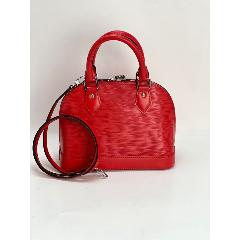 Red handbag with a matching strap on a light gray background
