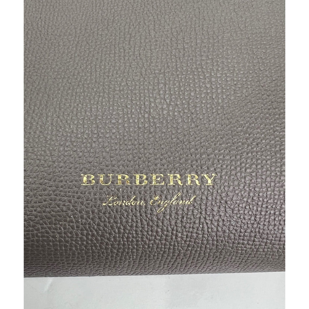Gray textured Burberry product with gold text on a white background