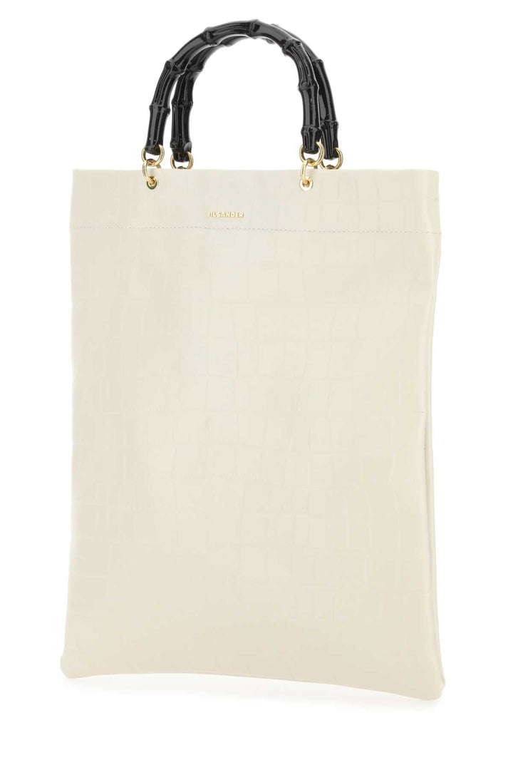 Beige tote bag with black bamboo handles on a white background