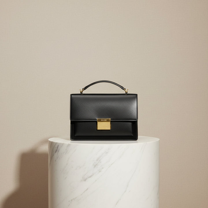 Black handbag with a gold clasp on a white background