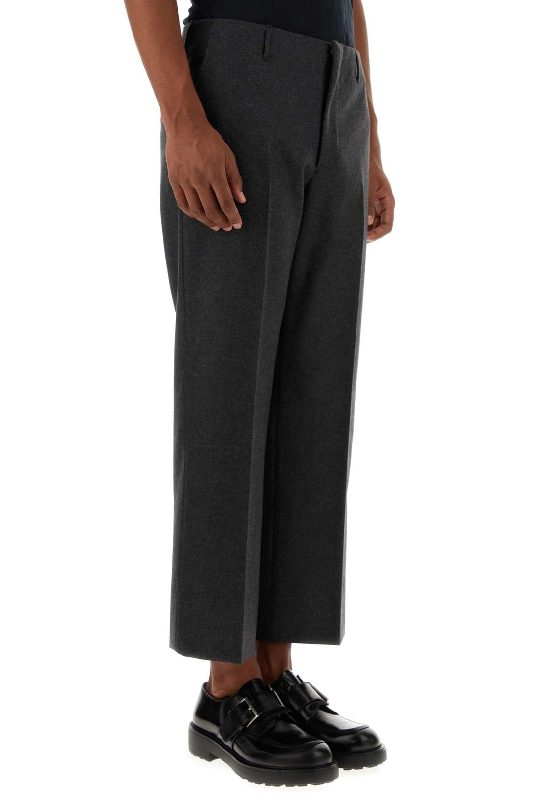 Person wearing dark gray wide-leg pants on a white background