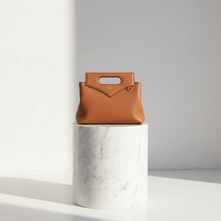 Brown handbag with a gold handle on a white background