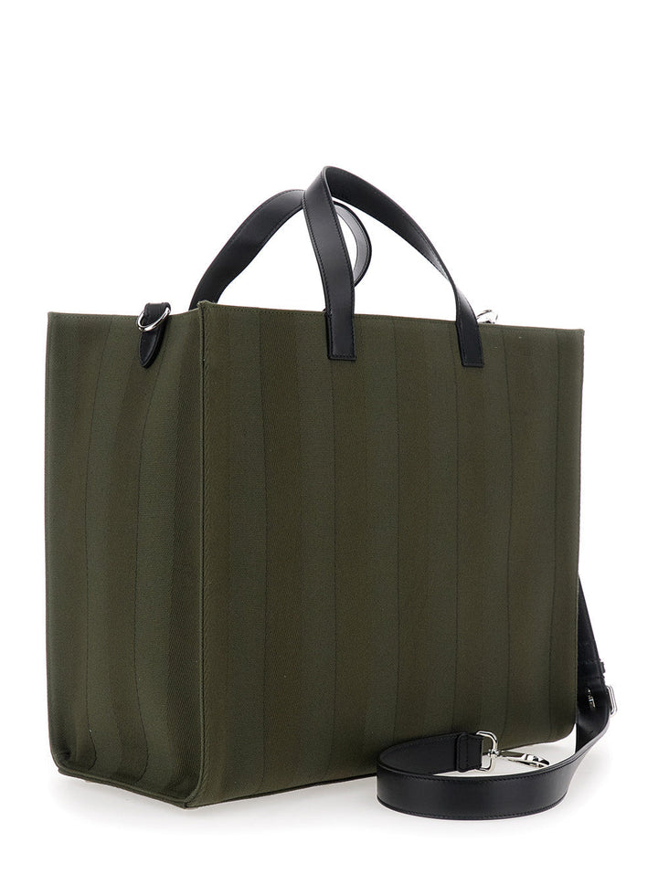 Green tote bag with black handles and strap on a white background