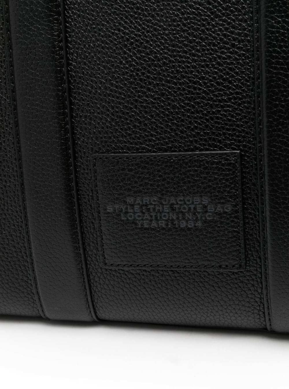 Close-up of a black leather bag with a brand label on a white background