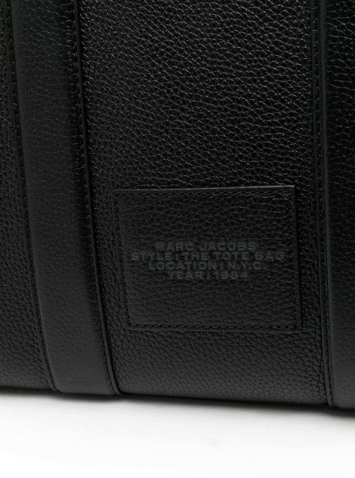 Close-up of a black leather bag with a brand label on a white background