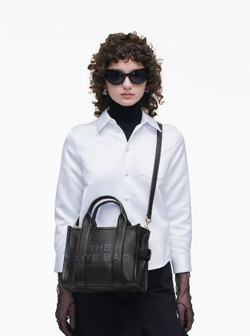 Woman holding a black handbag with 'The Kate Bag' branding on a white background