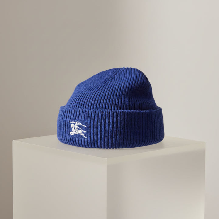 Blue knit beanie with a white logo on a white background