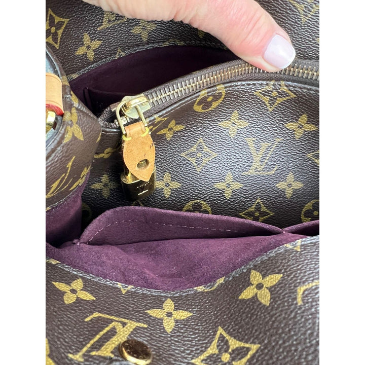 Close-up of a handbag with monogram pattern and purple interior.