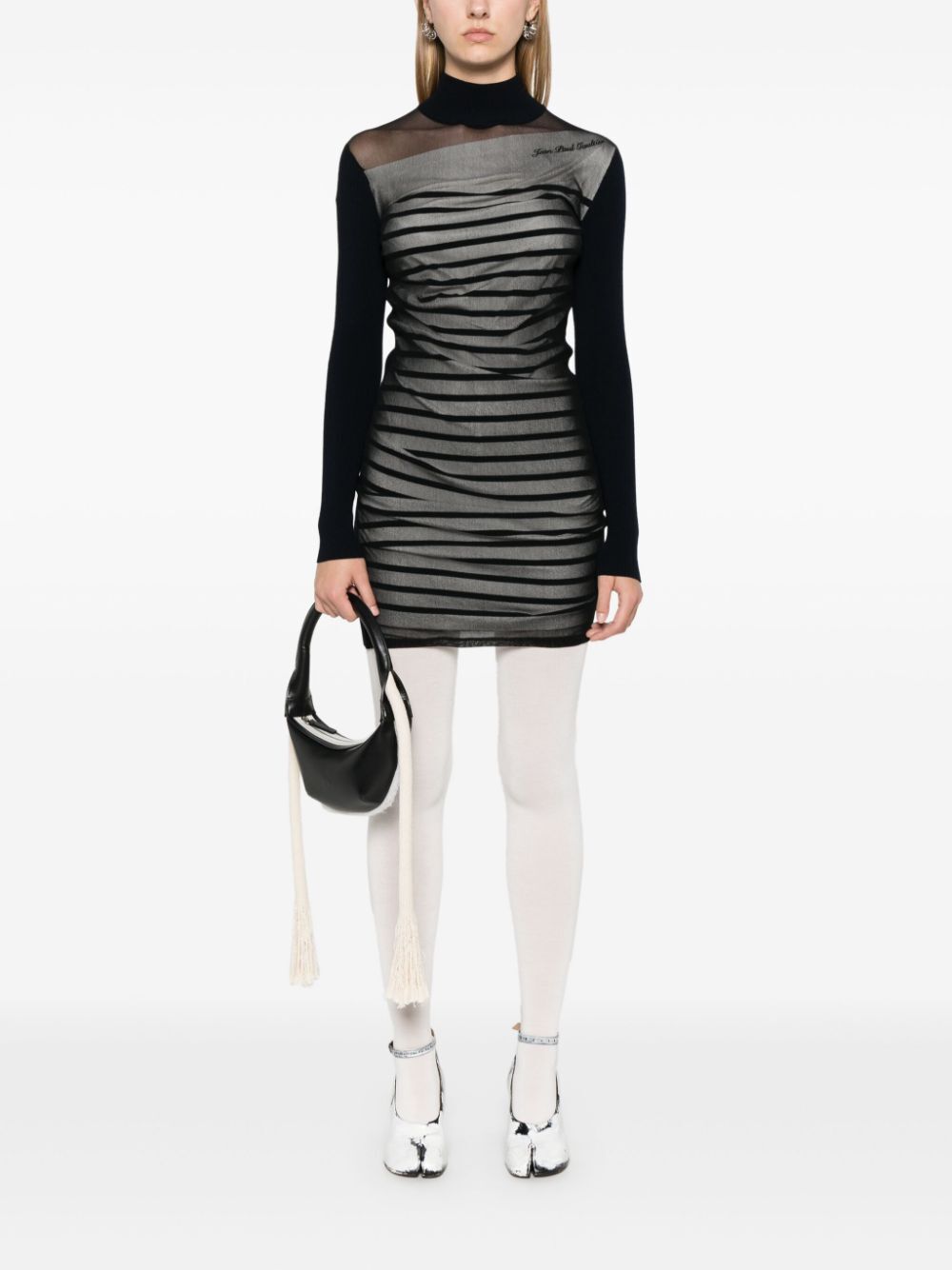 Person wearing a black and gray dress with sheer panels on a white background