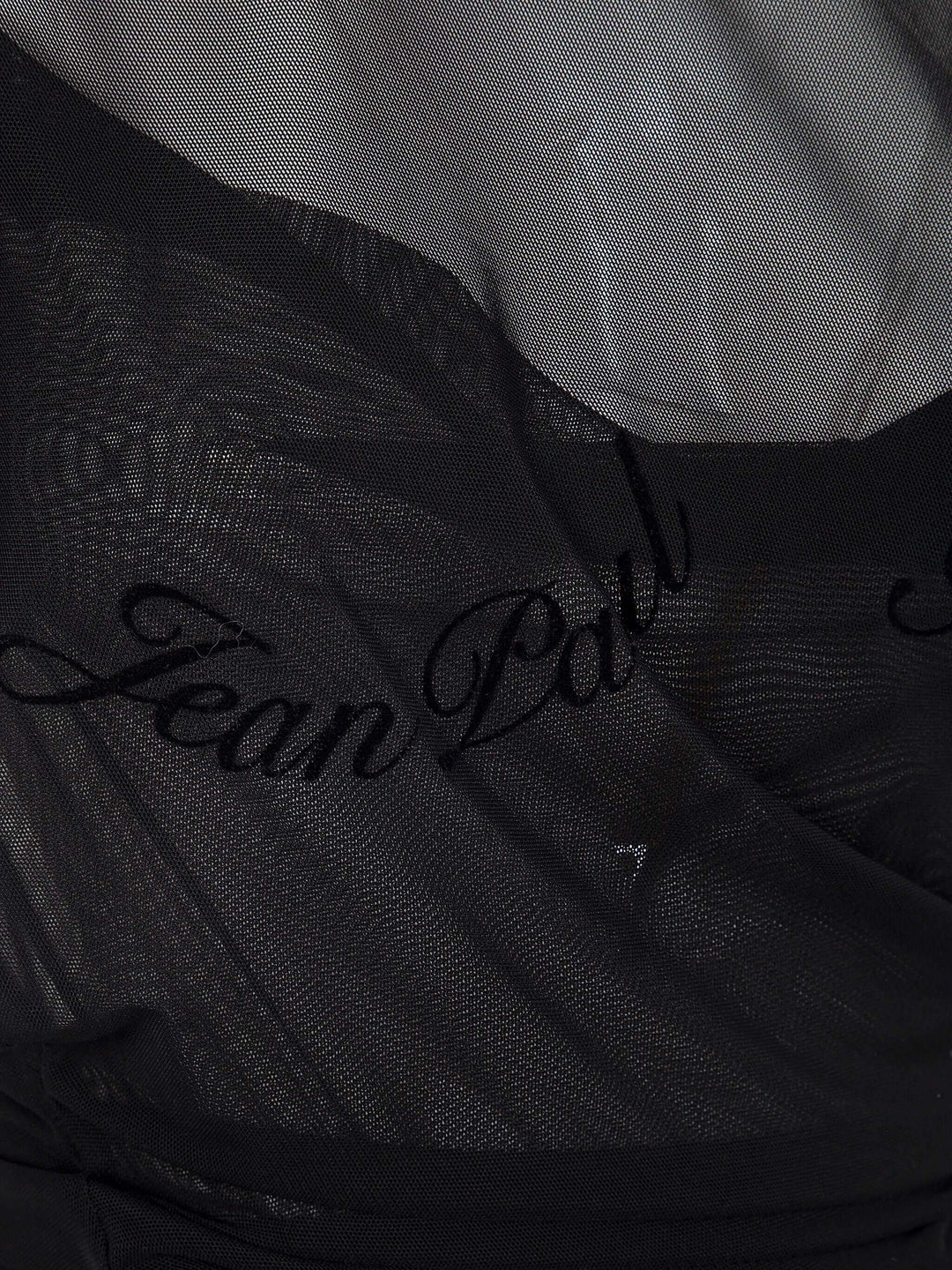 Black fabric with 'Jean Paul' embroidery on a textured background