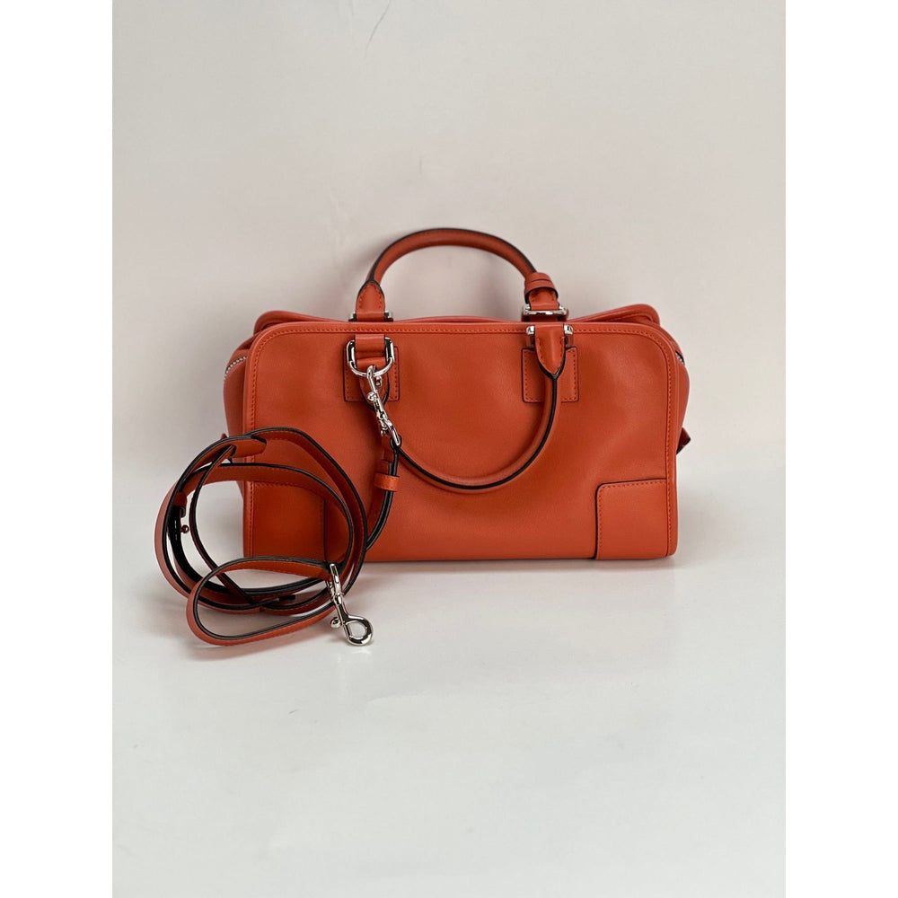 Brown leather handbag with a detachable strap on a light gray background