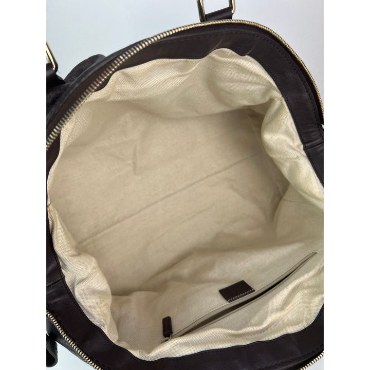 Open black leather bag with beige interior lining on a light gray background