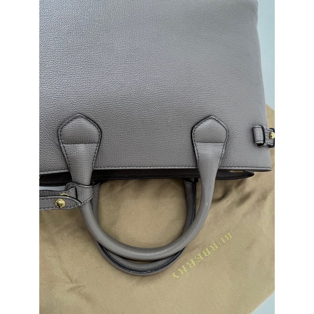 Gray handbag with gold accents on a beige surface
